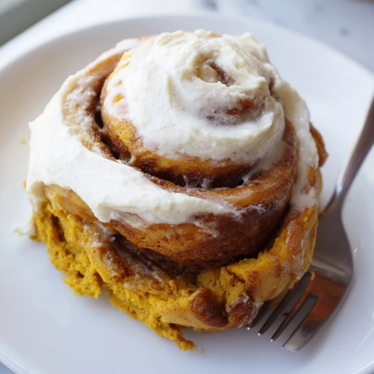 Warm pumpkin muffin filling peeks through beautifully swirled cinnamon rolls, perfect for breakfast.  