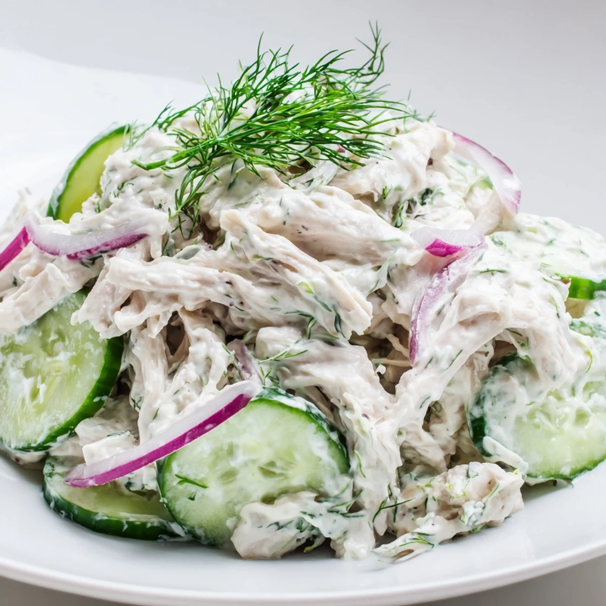 A close-up of creamy cucumber chicken salad with tender shredded chicken, crisp cucumber slices, and fresh dill in a light yogurt dressing, ready to serve chilled.