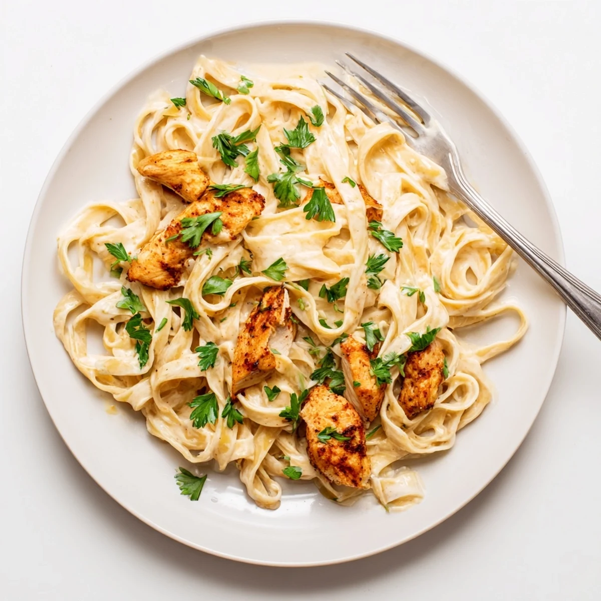 Cajun Chicken Alfredo showcases golden-brown, spice-rubbed chicken slices fettuccine with creamy Alfredo sauce and fresh parsley garnish.