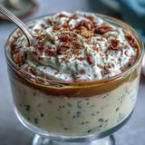 Chilled Hojicha Pudding topped with whipped cream and cocoa powder in a glass.