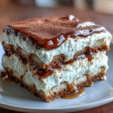 A freshly prepared Hojicha Tiramisu dessert plated with a fork, ready to be served at a dinner party.