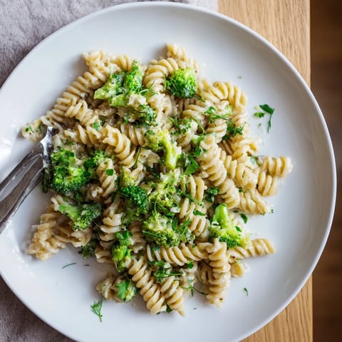 A steaming bowl of Green Goddess Broccoli Cheddar One-Pot Pasta with fresh herbs and creamy sauce.