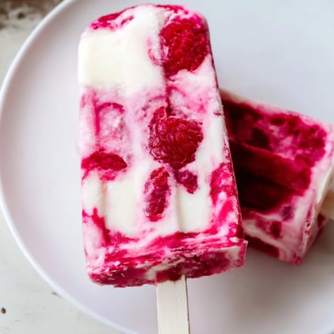 Frozen raspberry coconut ice pops, a creamy, layered dessert on a hot day.