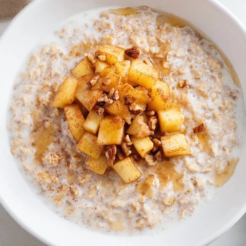 Steaming bowl of apple pie oatmeal, showing tender oats with caramelized apples and walnut garnish.