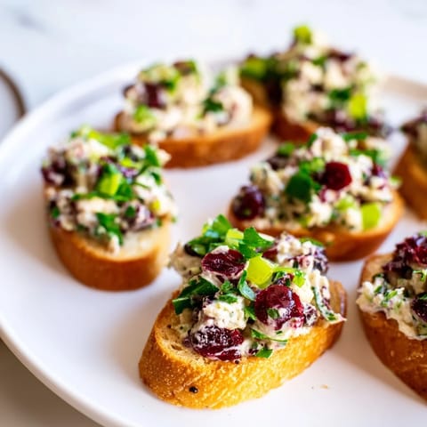 Crisp baguette slices topped with zesty Cranberry Jalapeño Tapenade, perfect for parties.  