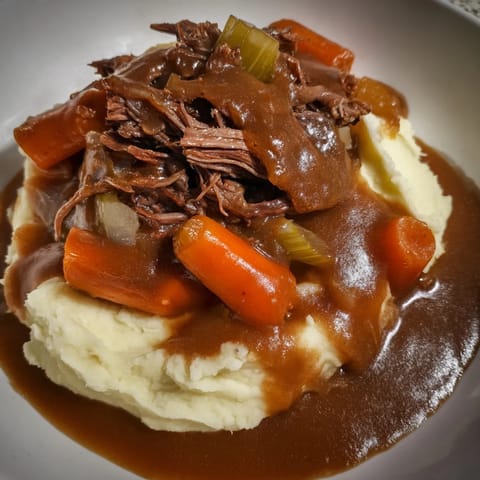 A close-up image shows juicy, shredded Slow Cooker Pot Roast, perfect for a cozy, comforting meal.