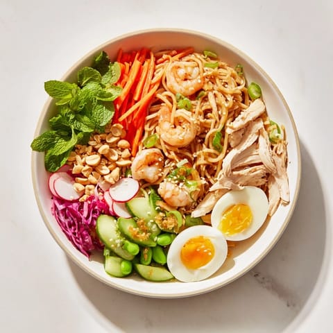 Beautifully arranged Asian Fusion Noodle Bowl features chicken, shrimp, and tofu with fresh, crisp garnishes.