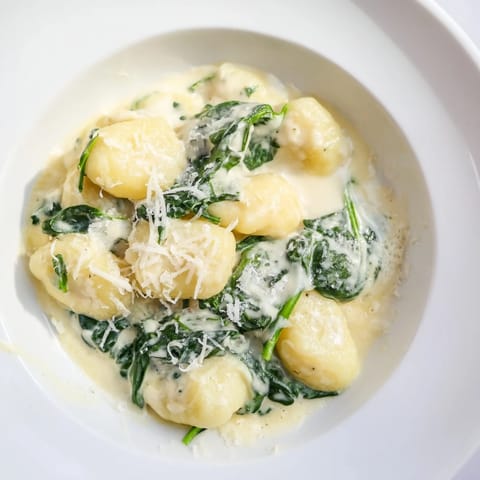 Fresh spinach melts into the rich garlic cream sauce coating pillowy gnocchi in a skillet.