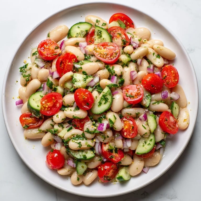 Creamy white bean salad featuring juicy tomatoes and vibrant green parsley: a fantastic side.