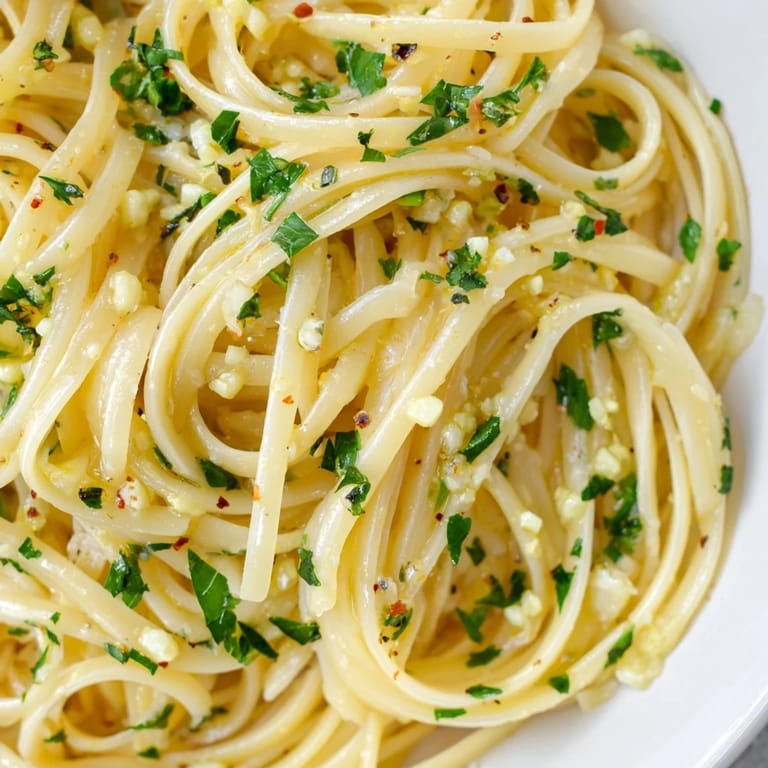 A bowl of delicious Garlic Butter Linguine, served with Parmesan cheese and fresh lemon wedges.