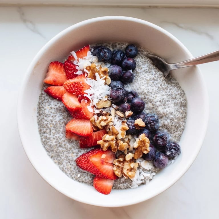 A glass of chia seed pudding garnished with fresh blueberries and raspberries, perfect for a healthy snack or dessert.