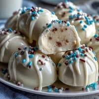 Festive white chocolate peanut butter Easter eggs decorated with colorful sprinkles on a pastel tray.
